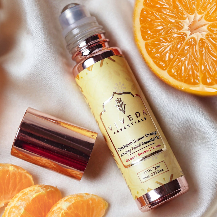 Viveda Essentials Patchouli Sweet Orange essential oil bottle with orange slices on a light background